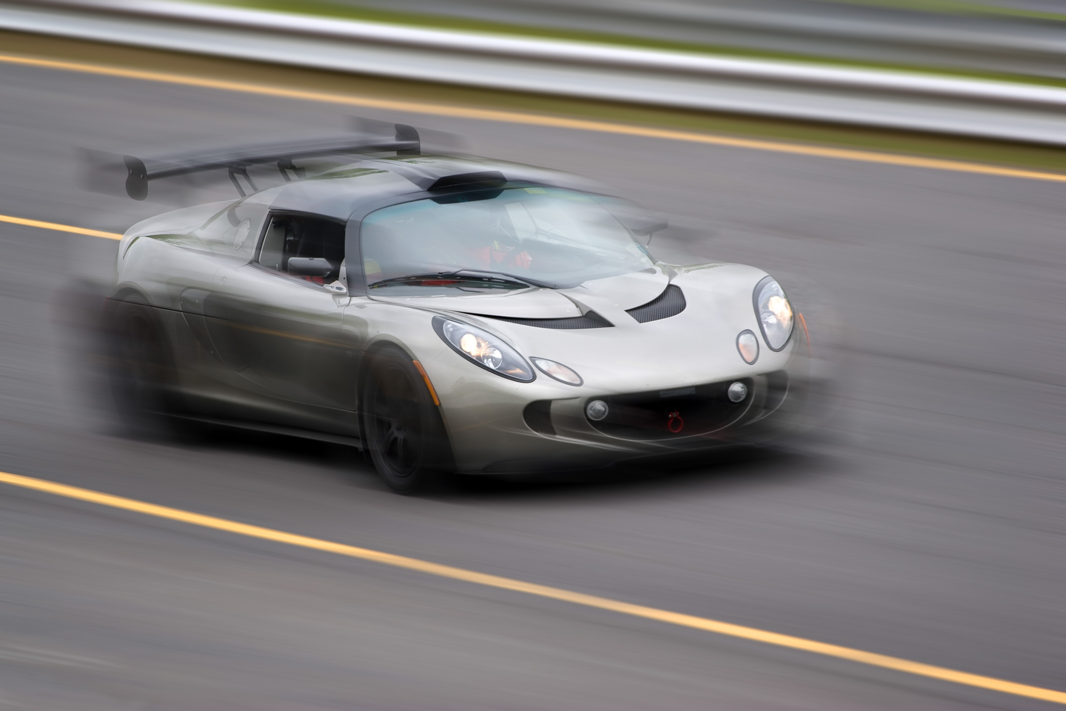A fast silver sports car speeding down the road. Slight motion blur....