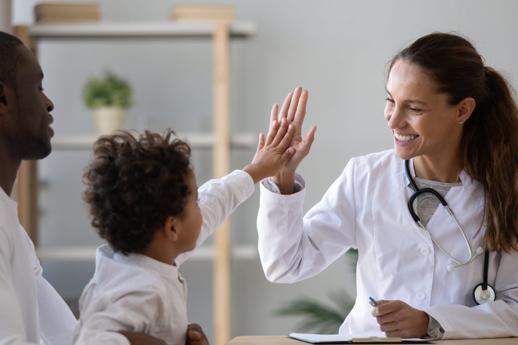 Smiling female doctor give high five to little biracial patient