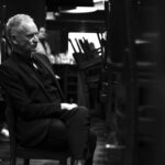 black and white photo of Sting with chairs blurred in the foreground
